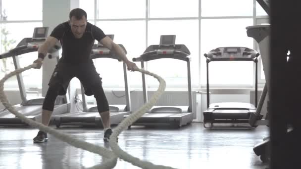 Movimiento lento del hombre con cuerda de batalla en gimnasio de entrenamiento funcional — Vídeo de stock