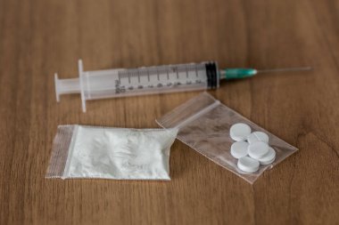 kaşık, plastik paket kokain ve ahşap masa üzerinde şırınga ile.