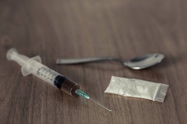kaşık, plastik paket kokain ve ahşap masa üzerinde şırınga ile.