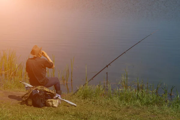Ψαράς με το καλάμι που αλιεύουν ψάρια, κάθεται δίπλα στο ποτάμι — Φωτογραφία Αρχείου