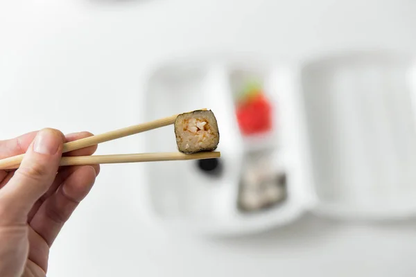 手保持与筷子、 卷、 寿司卷。筷子，姜，酱油容器交付. — 图库照片