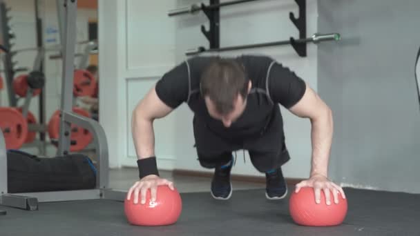 Fitness man doing push-ups exercise on the ball in gym — Stock Video