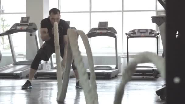 Hombre con cuerda de batalla en gimnasio de entrenamiento funcional — Vídeos de Stock