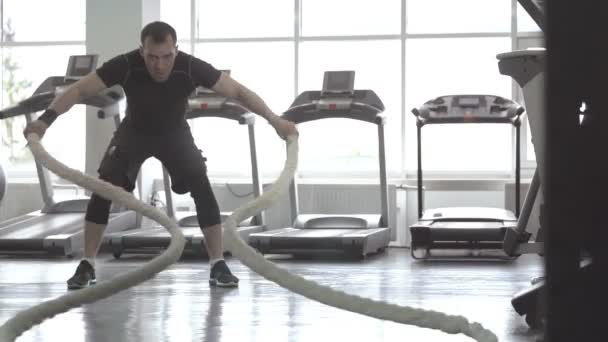 Hombre con cuerda de batalla en gimnasio de entrenamiento funcional — Vídeo de stock