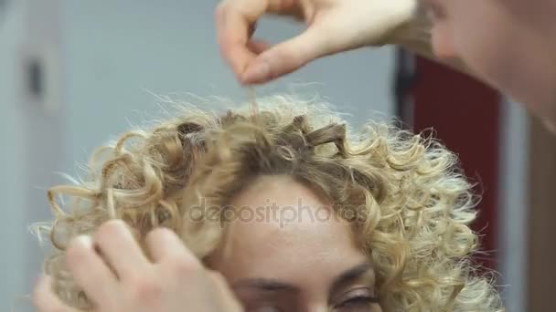 Schönes, blondes Mädchen mit langen Haaren, Friseur macht afrikanische Locken in einem Schönheitssalon. professionelle Haarpflege und Frisurengestaltung. — Stockvideo