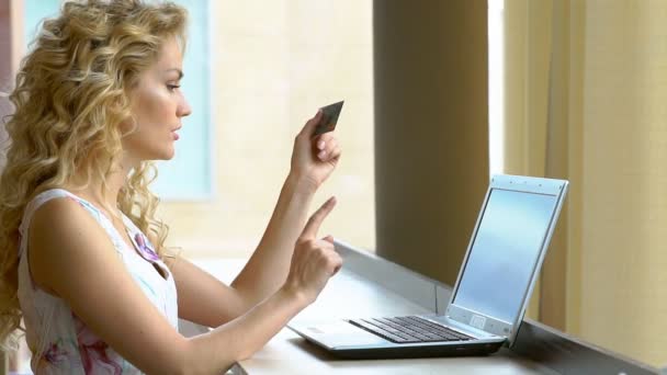 Joven hermosa chica en un vestido con una tarjeta de crédito y el uso de teclado de la computadora para las compras en línea — Vídeos de Stock