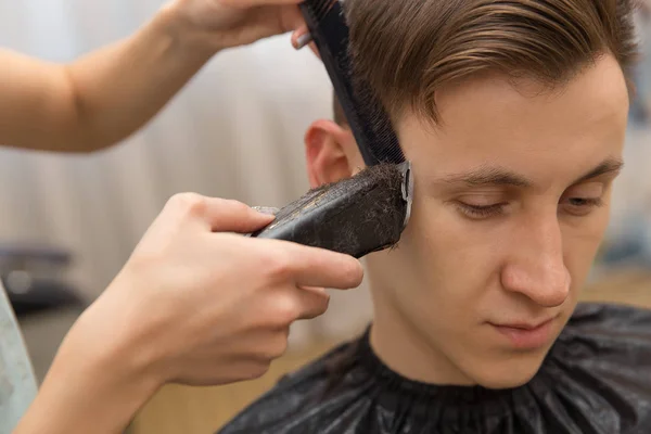 Mistrza tnie włosy mężczyzn w salonie fryzjerskim, sprawia, że fryzjer fryzurę dla młodego człowieka — Zdjęcie stockowe