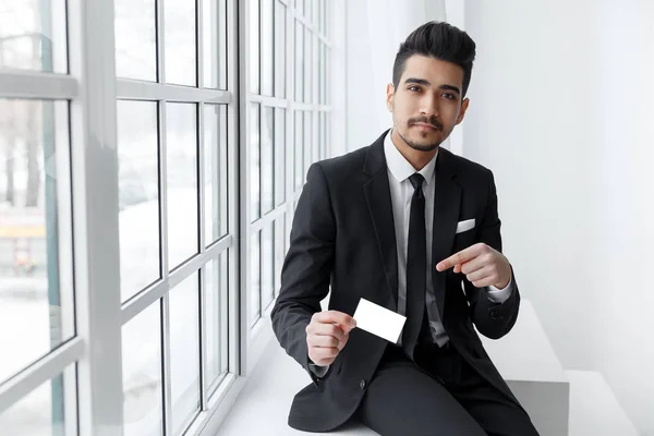 Joven hombre de negocios en traje con tarjeta de visita vacía — Foto de Stock