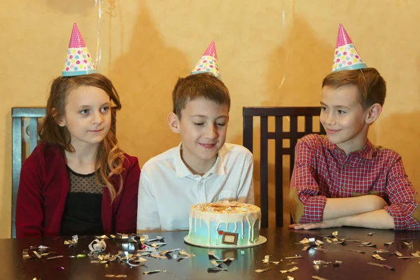 Menino e amigos olhando para bolo de aniversário. bolo de aniversário na mesa de férias na festa infantil — Fotografia de Stock