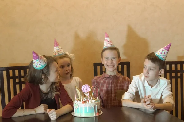 I bambini in cappelli festivi giocano e si divertono a una festa per bambini — Foto Stock