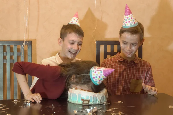 Crianças despreocupadas em uma festa de aniversário. menina afundou rosto no bolo de aniversário . — Fotografia de Stock