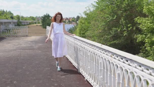Atrakcyjna dziewczyna w okularach słonecznych i białej sukni, chodzenie na zewnątrz — Wideo stockowe