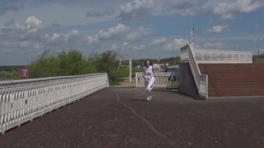 Kızıl saçlı kız eğlenir ve güneşli yaz günü sahiptir. beyaz yazlık elbise güzel kız. Ağır çekim