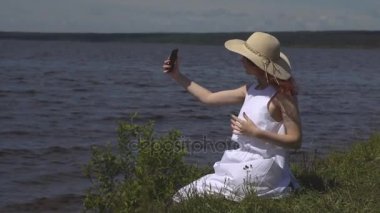 kendilerini bir cep telefonu fotoğraf çekme hasır şapkalı kız. güzel genç kadın nehirde fotoğrafı