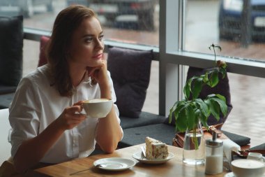 kahve ve tatlı pasta kafede oturan genç güzel kız. İş kadını dinlenme molası sırasında