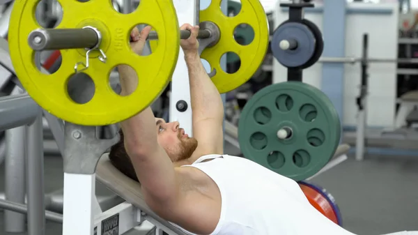 젊은 스포츠맨 바 벨 벤치 눌러 피트 니스 클럽에서 운동 하는 동안 하 고 맞는. 체육관에서 운동 하는 근육 질의 남자 — 스톡 사진
