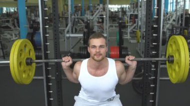 spor salonunda vücut geliştirme. bir halter ile ağız kavgası yapan adam. barbell ile egzersiz yaparak vücut geliştirmeci
