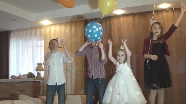 Los niños se divierten celebrando un cumpleaños. Un grupo de niños saltando, bailando y sonriendo en una fiesta de niños. Movimiento lento — Vídeos de Stock