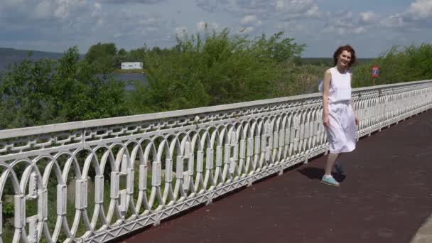 Jolie fille en lunettes de soleil et une robe blanche marchant à l'extérieur — Video