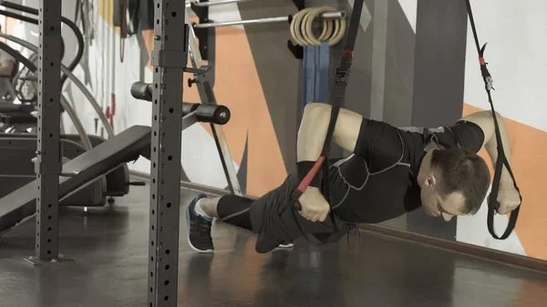 Atraktivní muž dělá crossfit push up s fitness popruhy v tělocvičně — Stock fotografie
