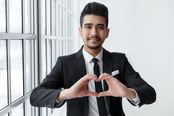 Giovane uomo d'affari innamorato mostra il segno del cuore — Foto Stock