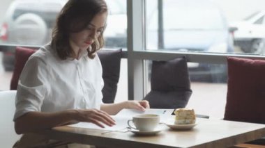 genç iş kadını bir kafede öğle yemeği molası sırasında dinlenme ve kadın moda dergisi leafing