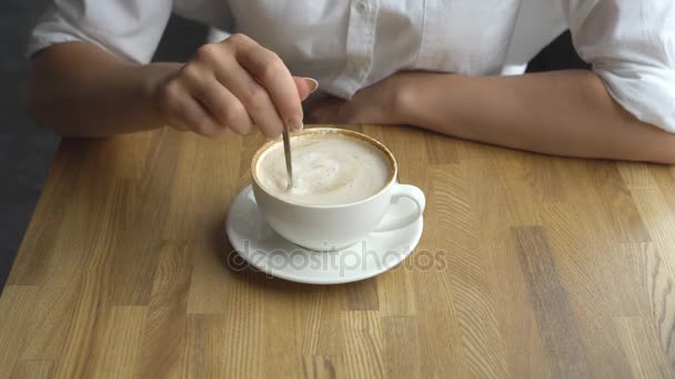 Uma jovem mulher bonita bebendo café em um café. Mão da menina mexendo açúcar no café de perto — Vídeo de Stock