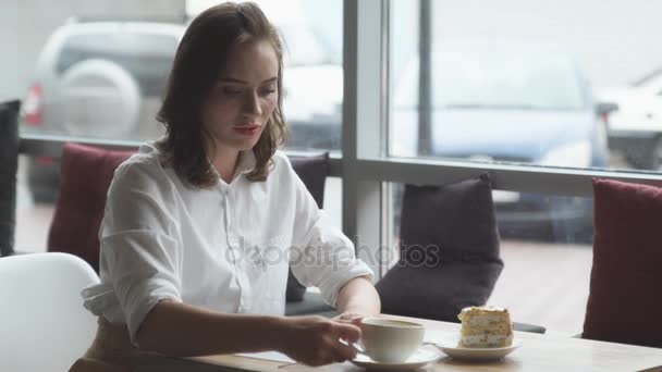 Attraktiv ung kvinna dricka färskt kaffe och läser en womens tidskrift i café — Stockvideo