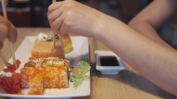Друзья едят суши и купаются в соусе — стоковое видео