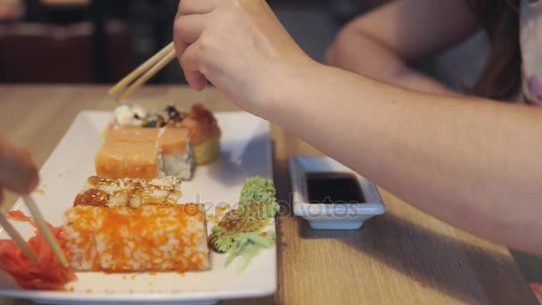 Amigos comiendo rollos de sushi en un restaurante japonés . — Vídeo de stock