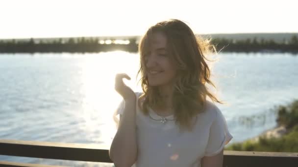 Красива дівчина в окулярах на набережній і посміхається на заході сонця — стокове відео