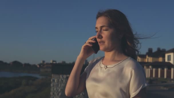 Menina séria falando ao telefone no pôr do sol . — Vídeo de Stock
