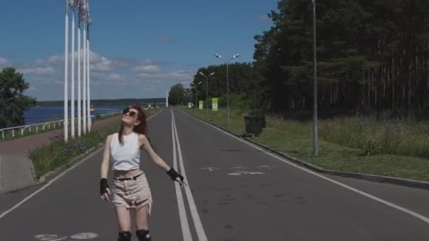 Menina bonita com patinação de rolo de cabelo vermelho ao ar livre, menina hipster sorrindo. 4k — Vídeo de Stock