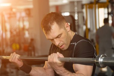 Eğitim pazı kaldırma halter güneş ışığı ile bir spor salonunda yakışıklı genç adam