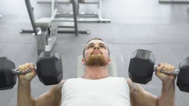 Göğüs dumbbells ile egzersiz yaparak atlet. jimnastik salonu kas delikanlı trenler.