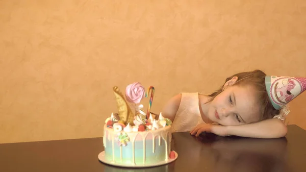 Festa de aniversário das crianças. Uma menina a olhar para o bolo. celebração familiar . — Fotografia de Stock