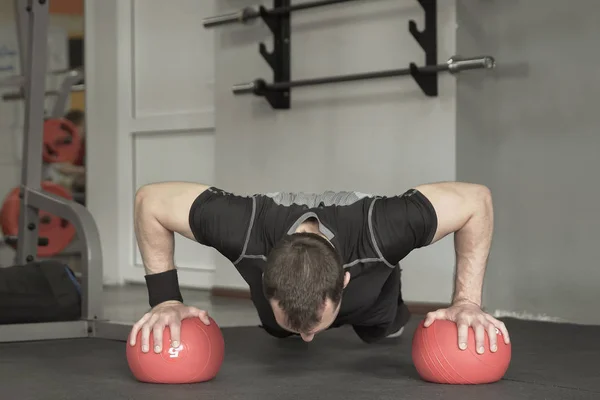 Siyah şort ve tişört giyen sporcu şınav egzersiz spor salonunda topa yapmak. — Stok fotoğraf