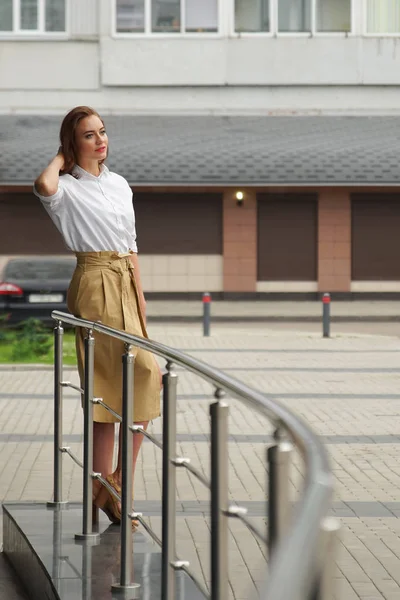 Stylisches brünettes Mädchen steht auf der Straße am Geländer — Stockfoto