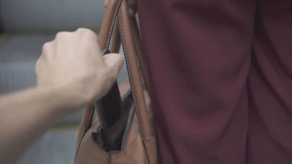 Pickpocket thief is stealing smartphone from orange handbag. — Stock Photo, Image