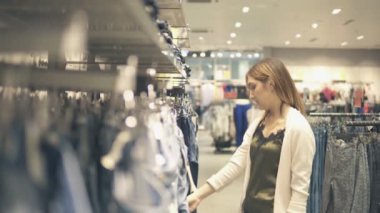Genç kız moda alışveriş merkezinde alışveriş yeni giysiler seçmek.