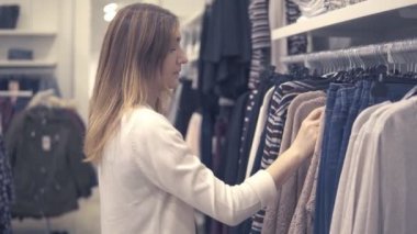 Yeni giysiler seçmek moda alışveriş merkezinde alışveriş genç güzel kadın