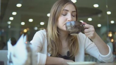 güzel bir genç kadın bir kafede kahve içme.
