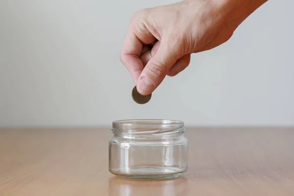 Χέρι βάζοντας χρήματα κέρμα στο άδειο γυάλινο βάζο — Φωτογραφία Αρχείου