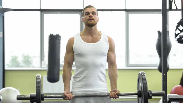 Atleta fazendo exercício para bíceps com barra. jovem homem musculoso treina no ginásio — Fotografia de Stock