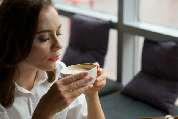 Ładna dziewczyna cieszy, aromatyczna kawa i słodkie ciasto siedząc w kawiarni. Biznes kobieta odpoczynku podczas przerwy. — Zdjęcie stockowe