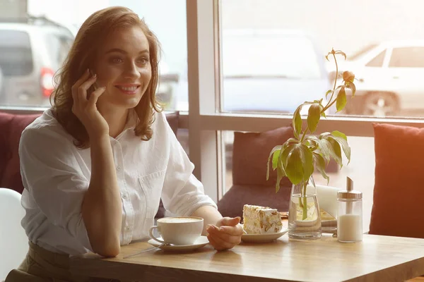 Junges Mädchen, das Kaffee trinkt und im Café mit dem Handy telefoniert. Geschäftsfrau in der Mittagspause — Stockfoto