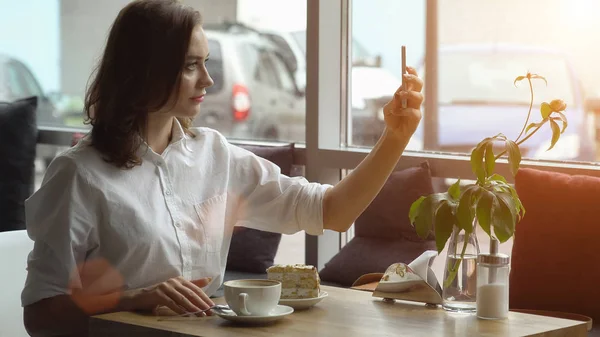 Junge schöne Frau macht Selfie mit Kamera Smartphone sitzt in Kaffeehaus — Stockfoto