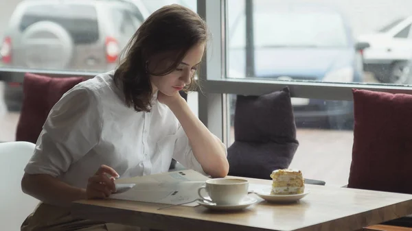 Młoda kobieta jest odpoczynek w trakcie przerwa obiadowa w kawiarni i zaglądać magazynu mody dla kobiet — Zdjęcie stockowe