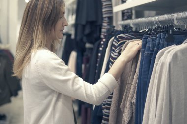 Yeni giysiler seçmek moda alışveriş merkezinde alışveriş genç güzel kadın