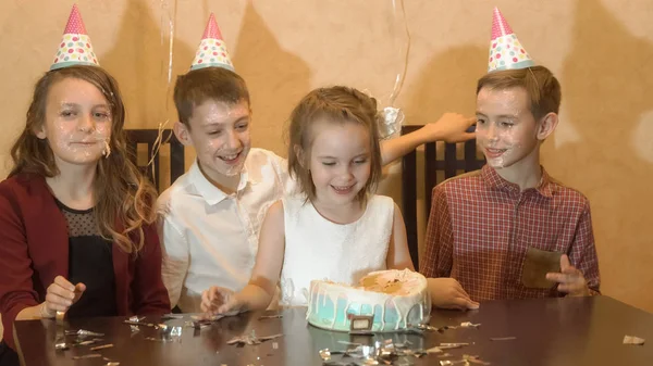 Kaygısız çocuk bir doğum günü partisinde. arkadaşlar dunked doğum günü kızı yüz doğum günü pastası. — Stok fotoğraf